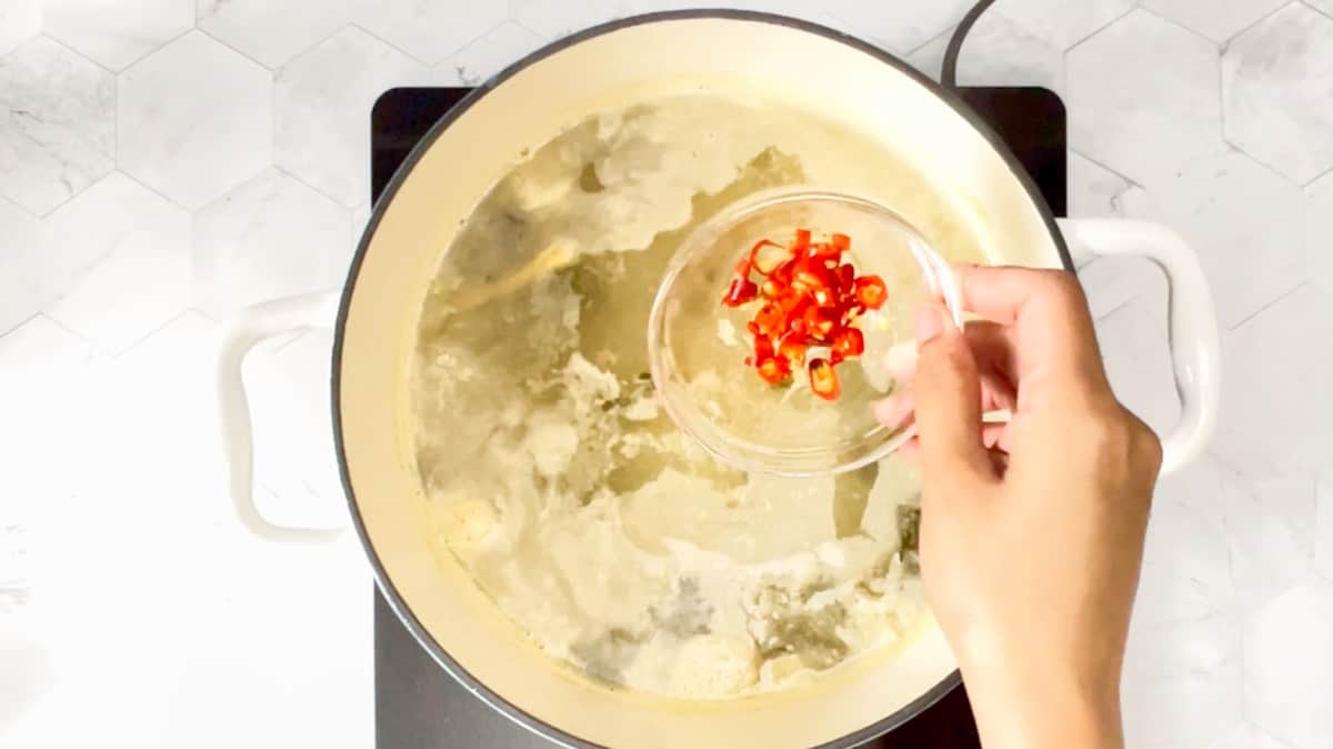 Adding chopped Thai chilies to the boiling liquid