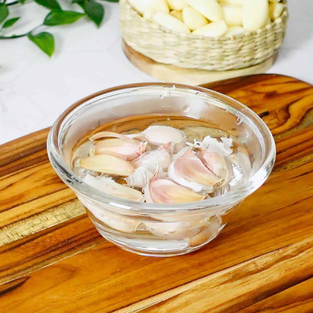 Unpeeled garlic cloves soaking in a bowl filled with warm water.