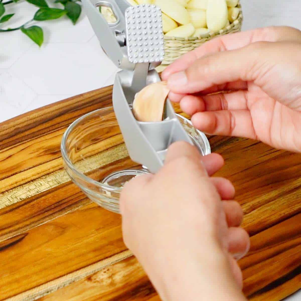 Placing an unpeeled garlic clove in a garlic press.