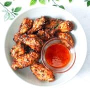 a plate with hot honey lemon pepper wings and a small bowl of honey sriracha sauce