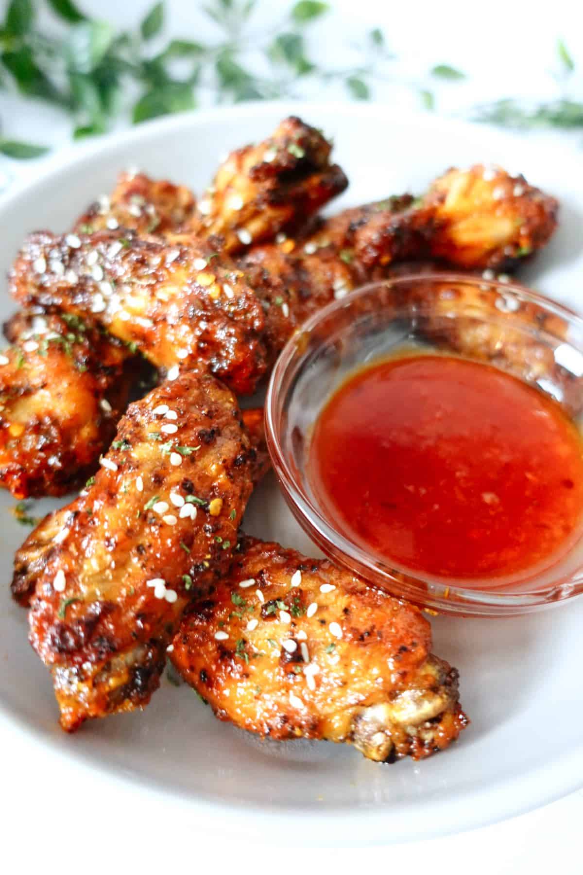 hot honey lemon pepper wings in a plate with a small bowl of honey sriracha sauce