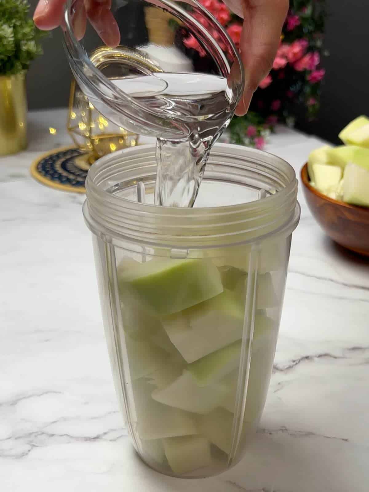 adding vinegar to green papaya cubes that are in a blender jar