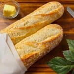 a pair of baguettes that have been reheated in an air fryer, partially wrapped in some paper, resting on a table