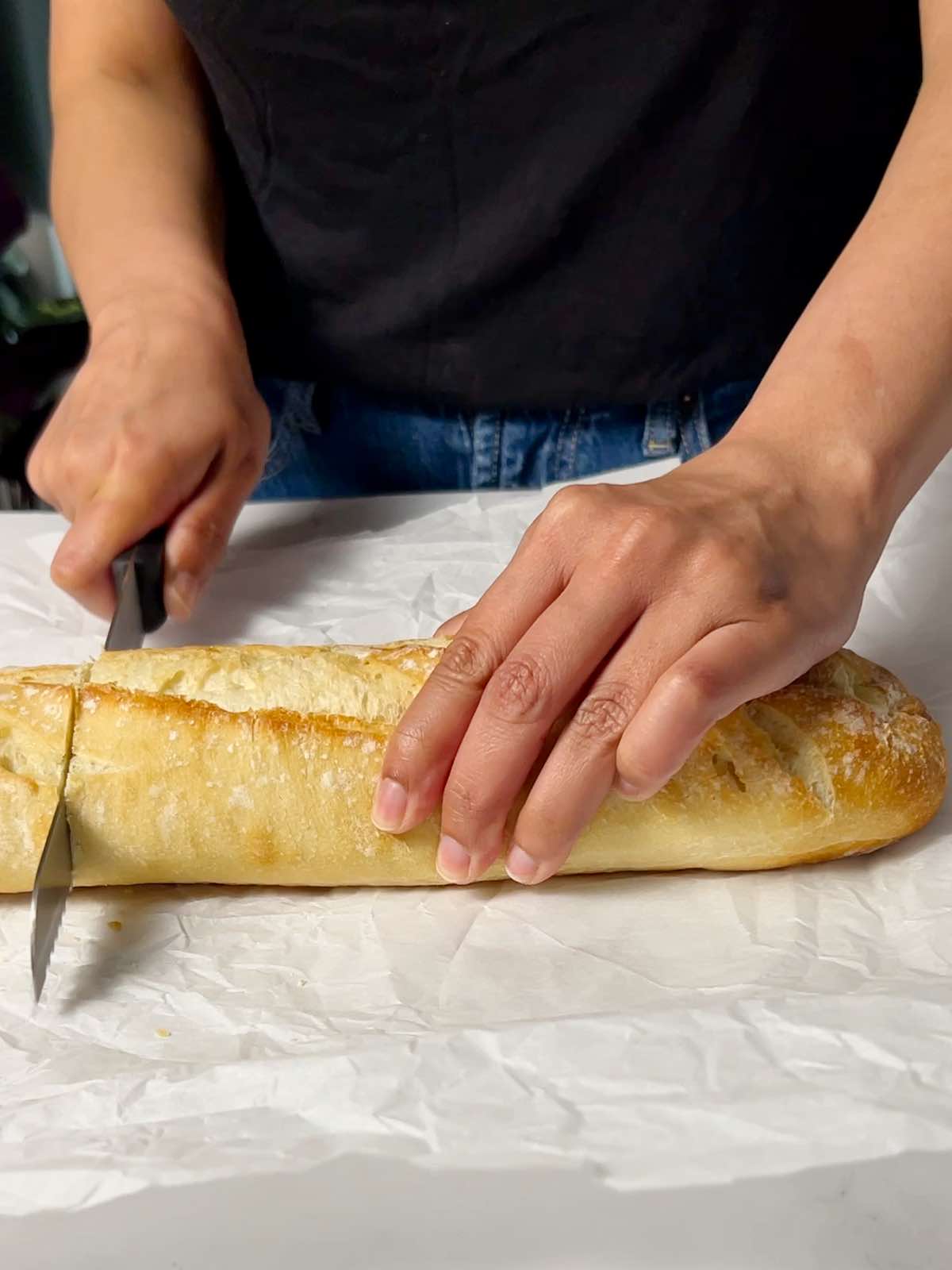 cutting a baguette into half so it fits the air fryer basket