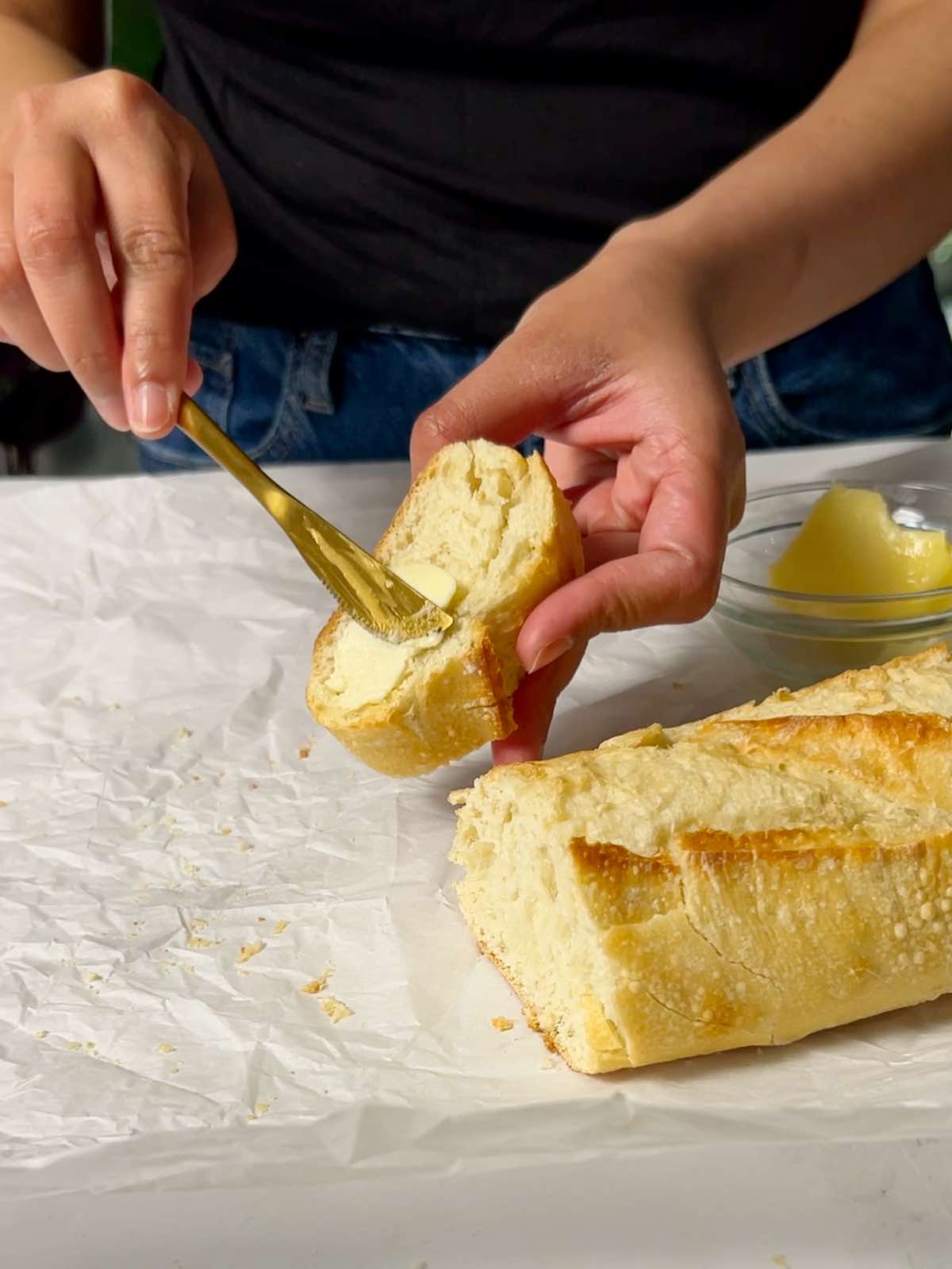applying butter to a slice of baguette that has been just softened in the oven