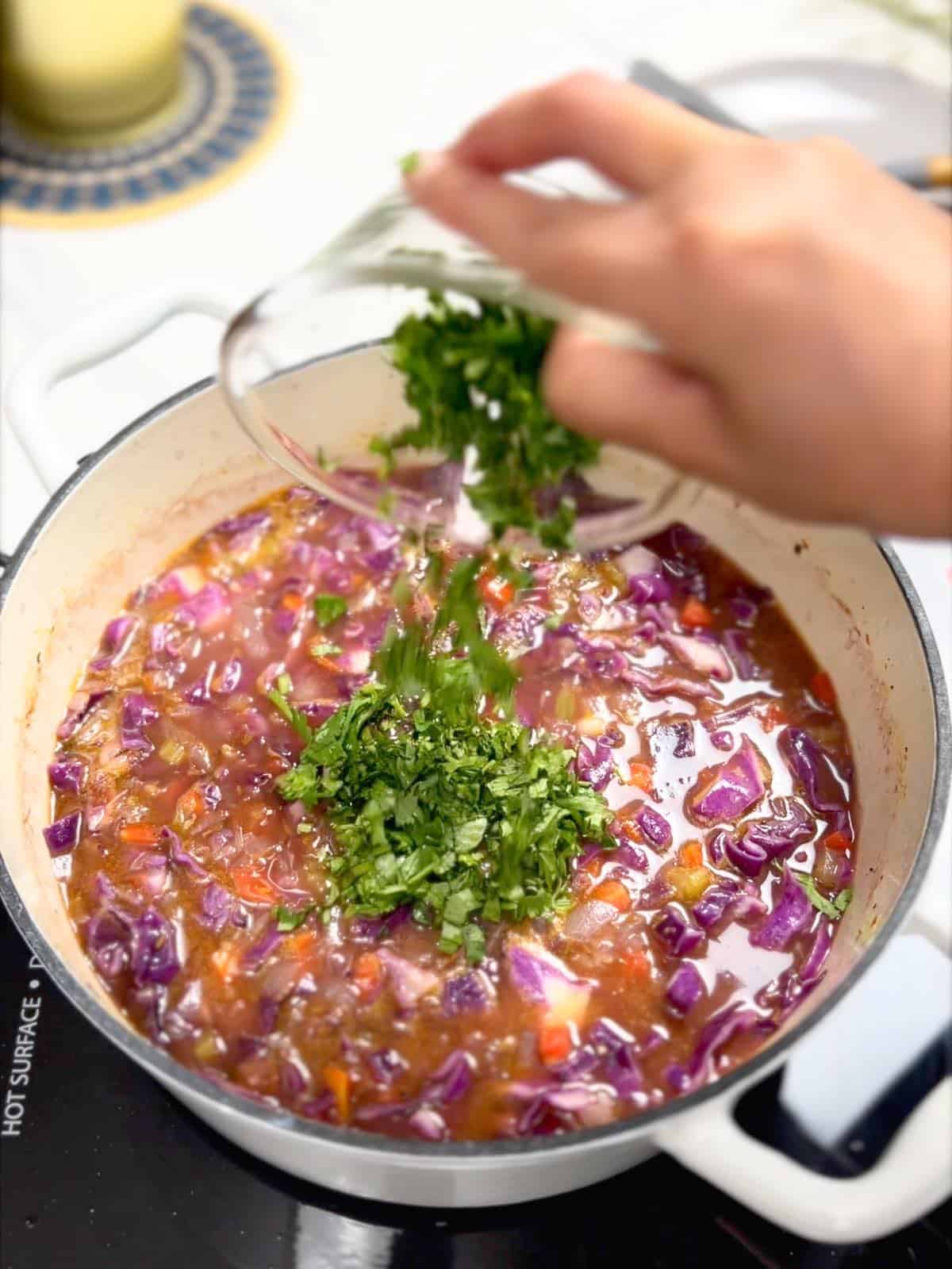 adding chopped cilantro to the soup