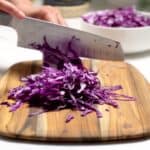 cutting purple cabbage with a chef's knife on a cutting board