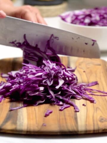 cutting purple cabbage with a chef's knife on a cutting board