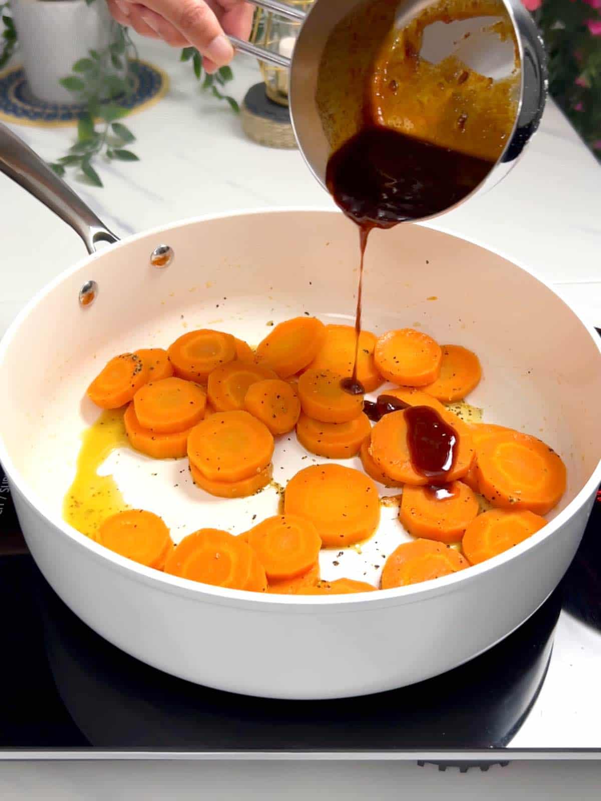 adding hot honey glaze to cooked carrots
