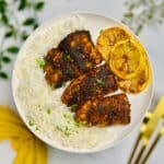 a plate of blackened haddock alongside rice and lemon