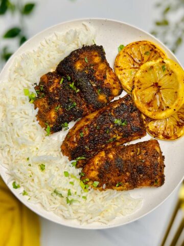 a plate of blackened haddock alongside rice and lemon