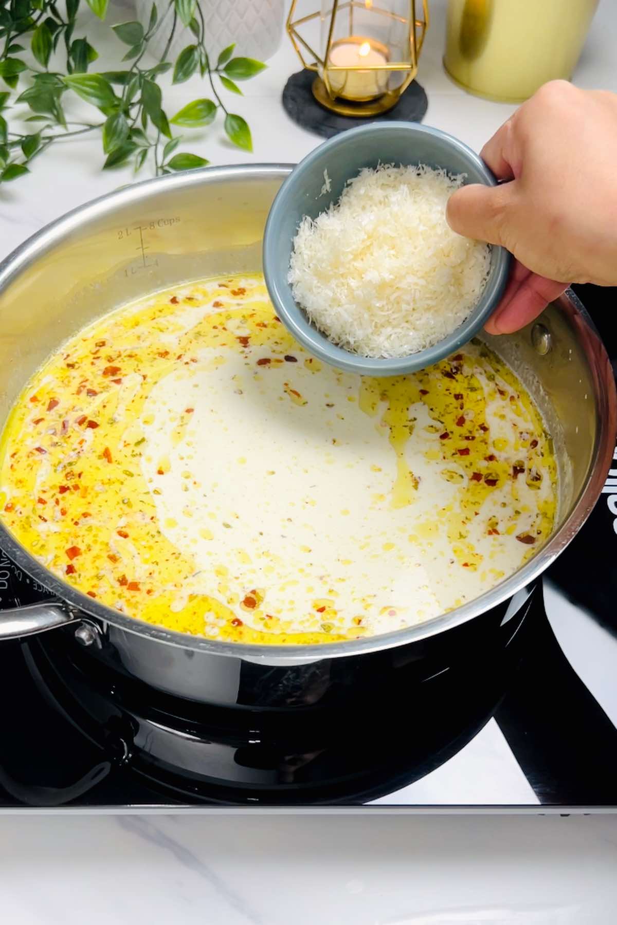 adding parmesan to creamy sauce in the skillet