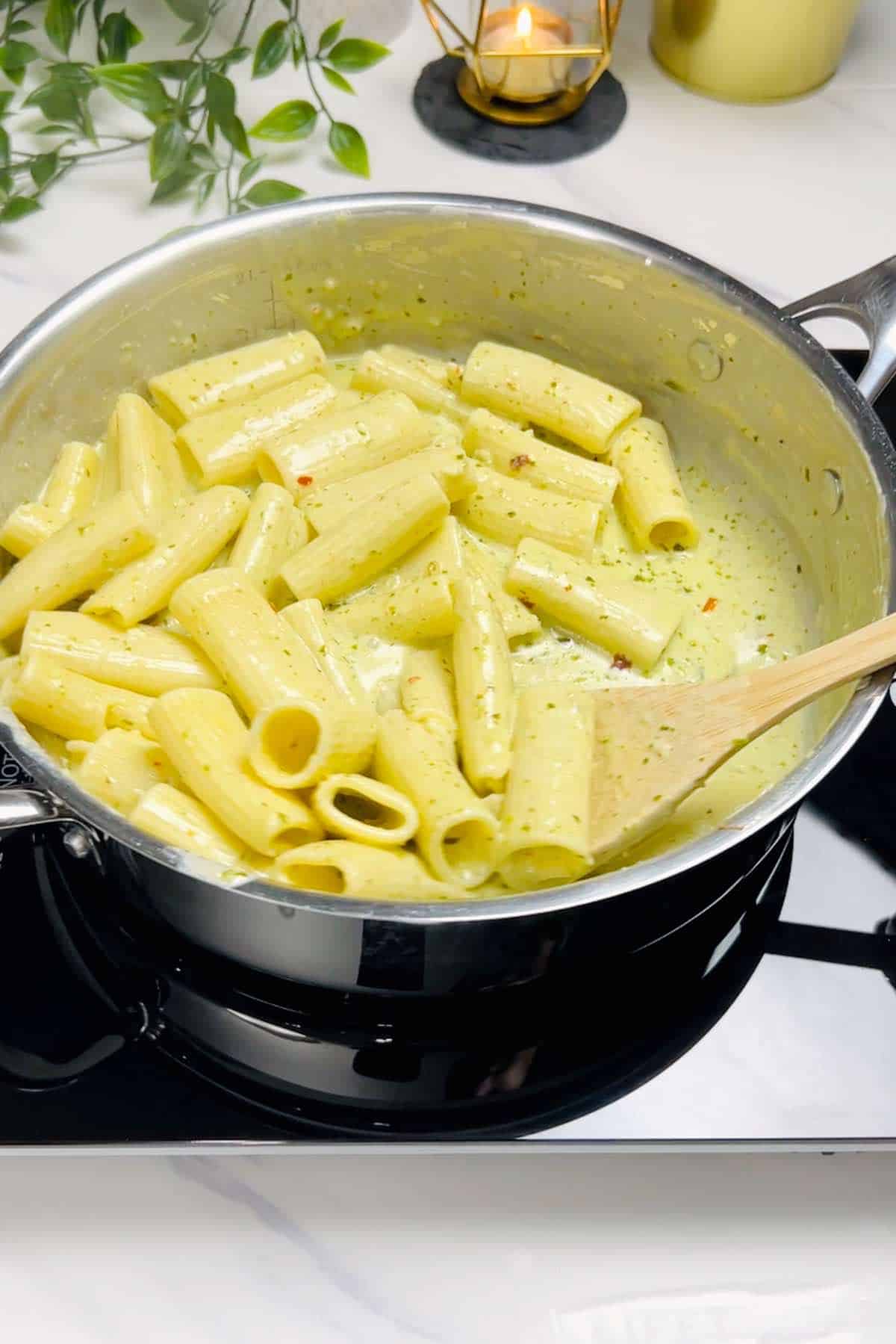 mixing cooked pasta and truffle pesto sauce together