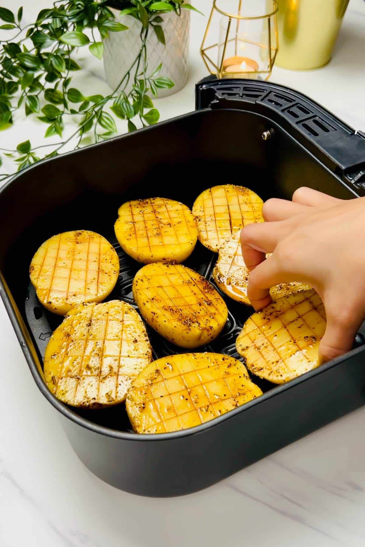 placing seasoned potato halves in an air fryer basket