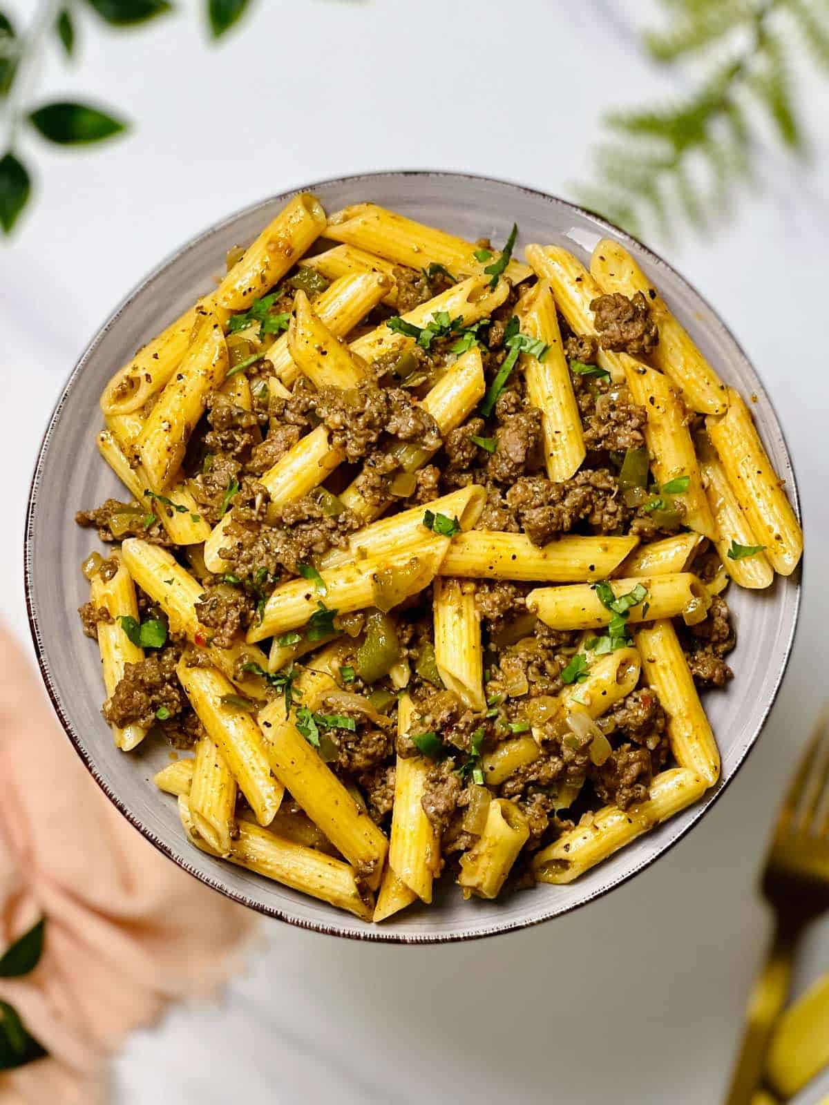 a plate full of ground beef pesto pasta
