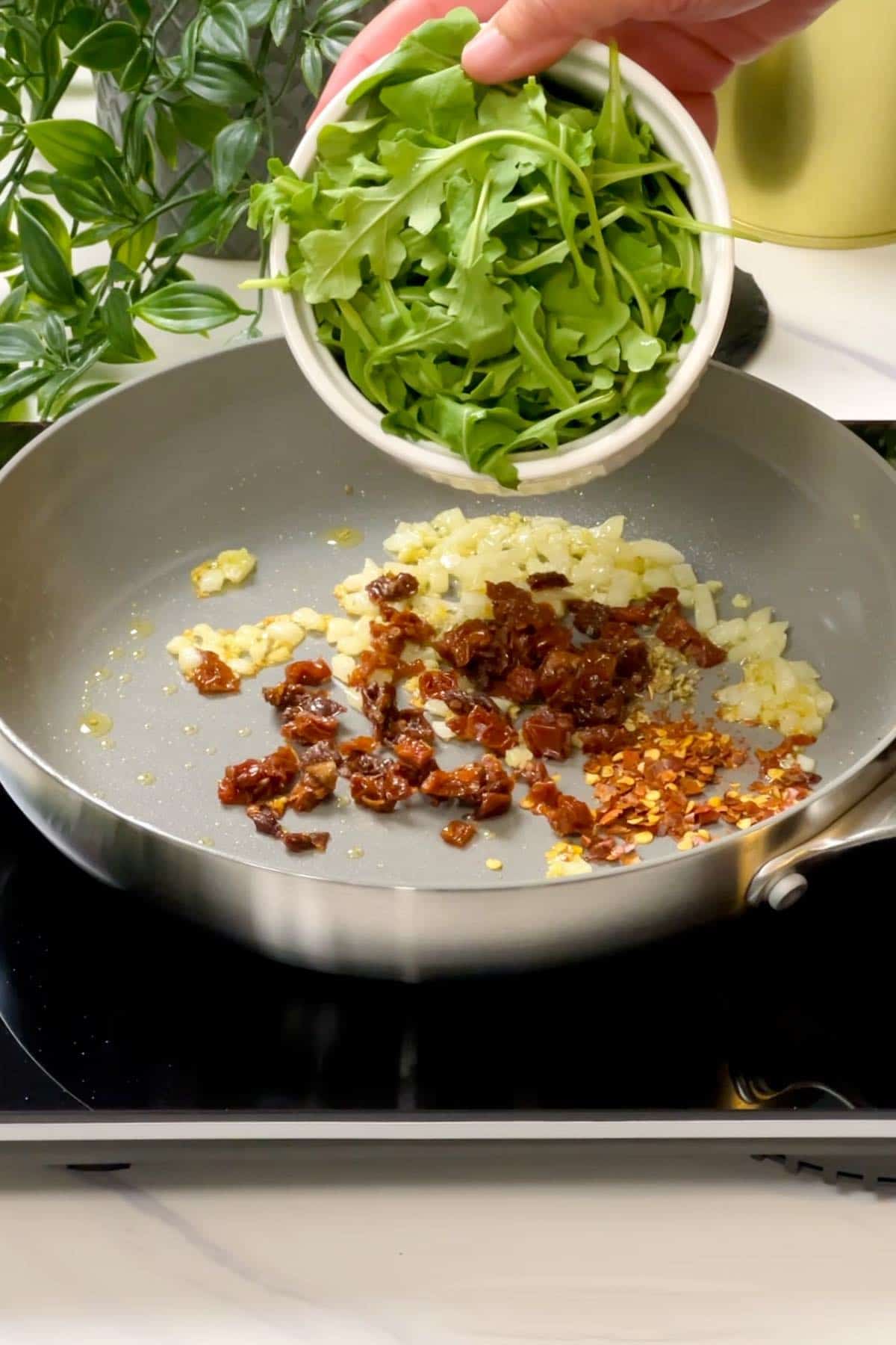 adding arugula to the rest of the filling ingredients in the pan
