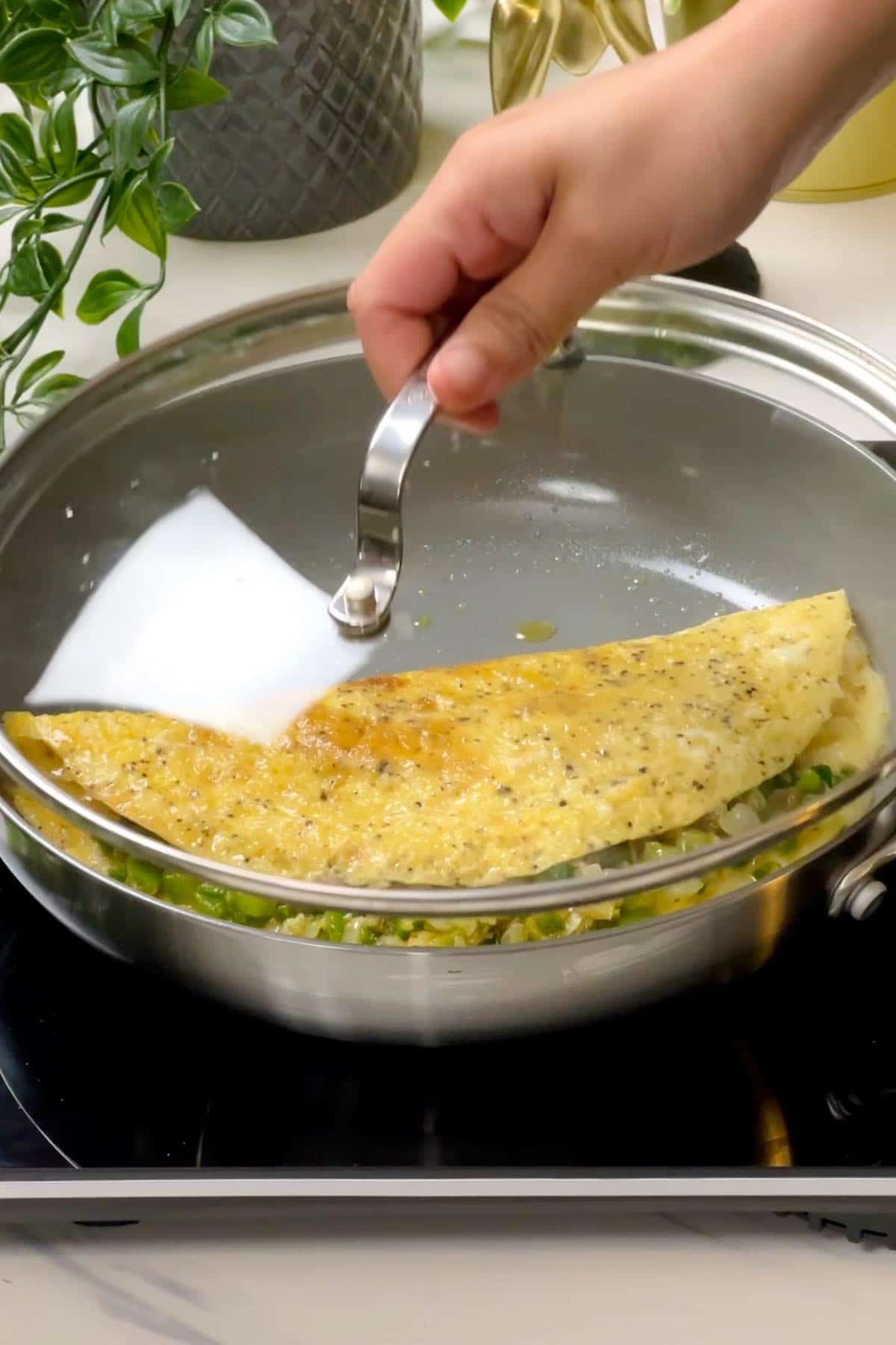 putting lid on the pan containing jalapeno omelette