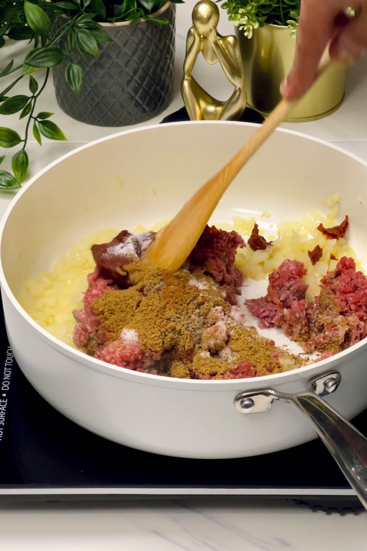 mixing together ground beef and seasonings in the skillet