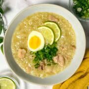 arroz caldo served with boiled egg, scallion and lime slices on top