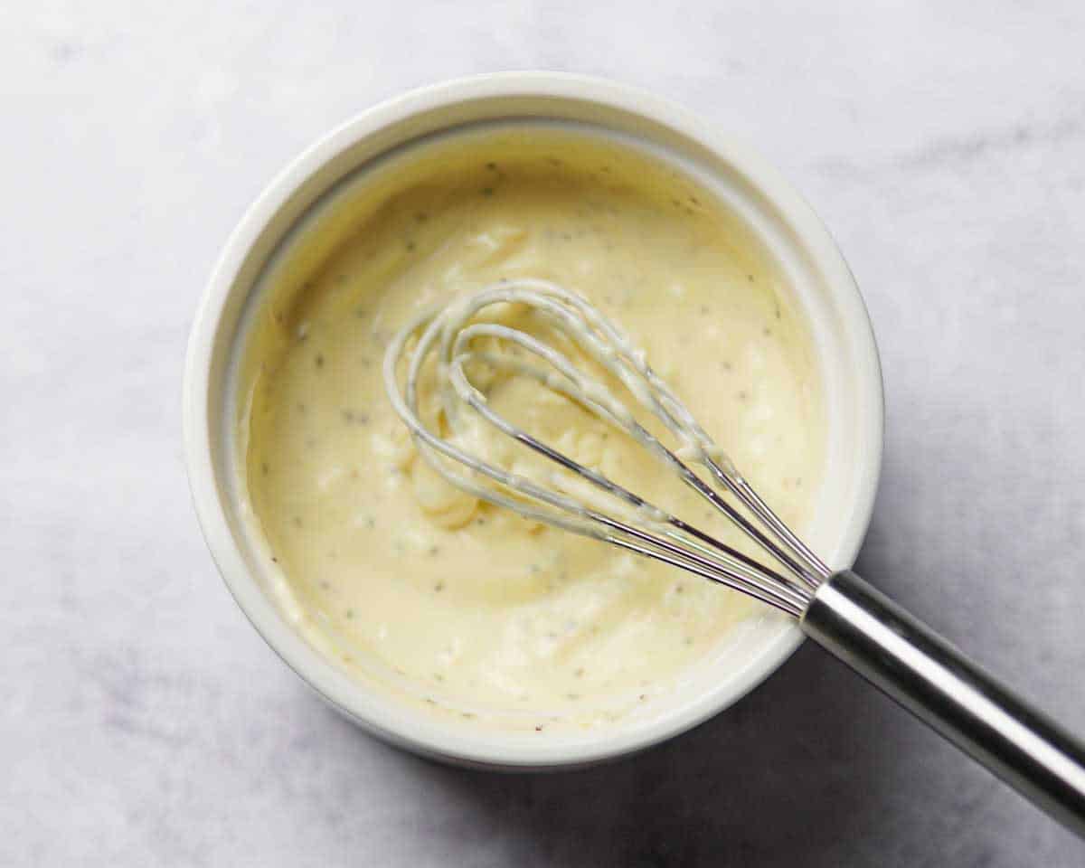 a whisk in a bowl that has truffle aioli ingredients mixed together