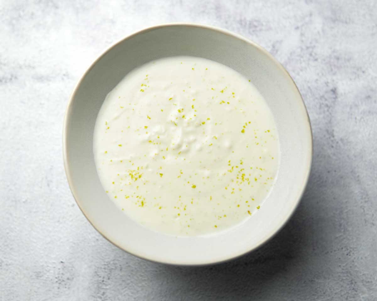 bowl containing yogurt mixed with lime zest, garlic, and seasonings