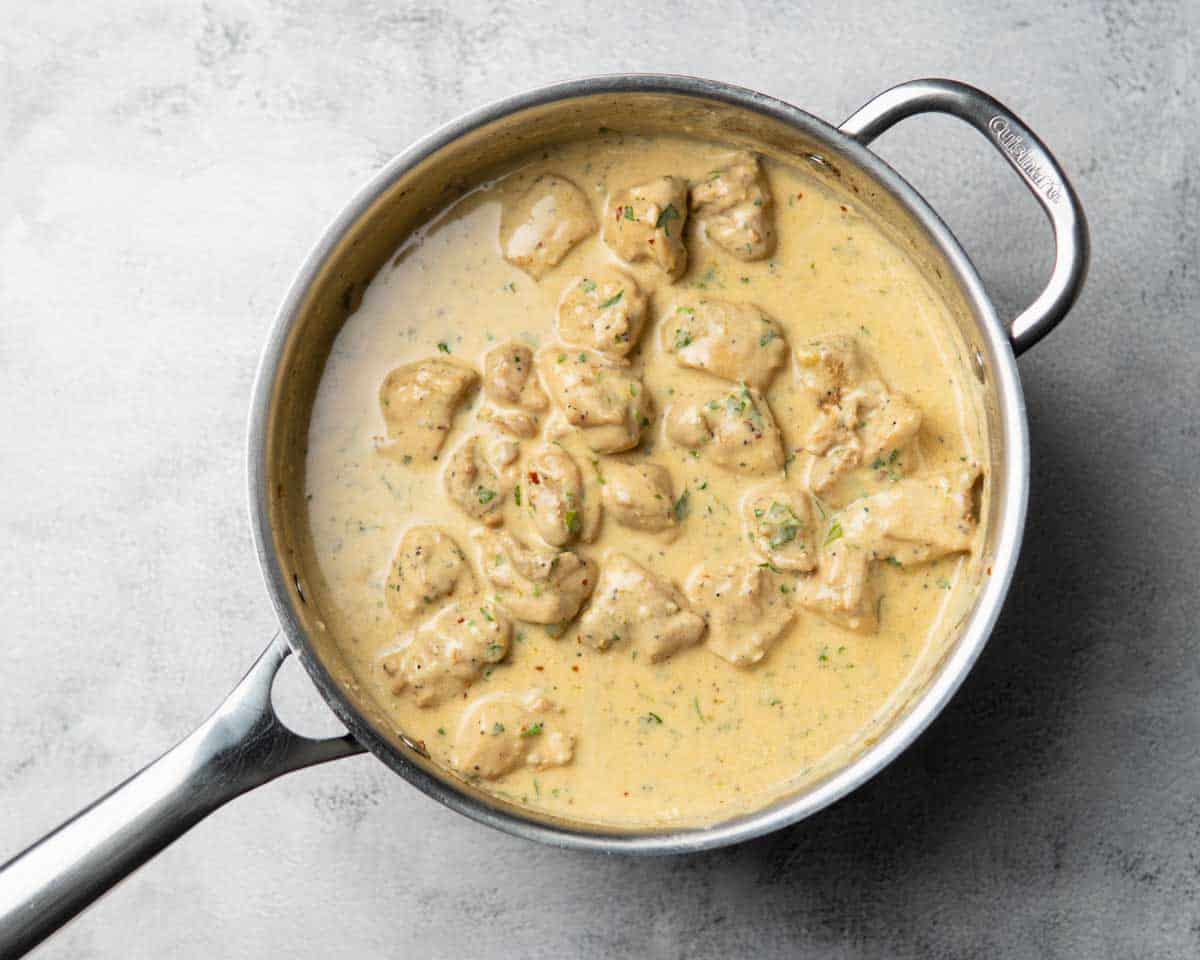 a skillet containing chicken pieces in creamy garlic lime sauce