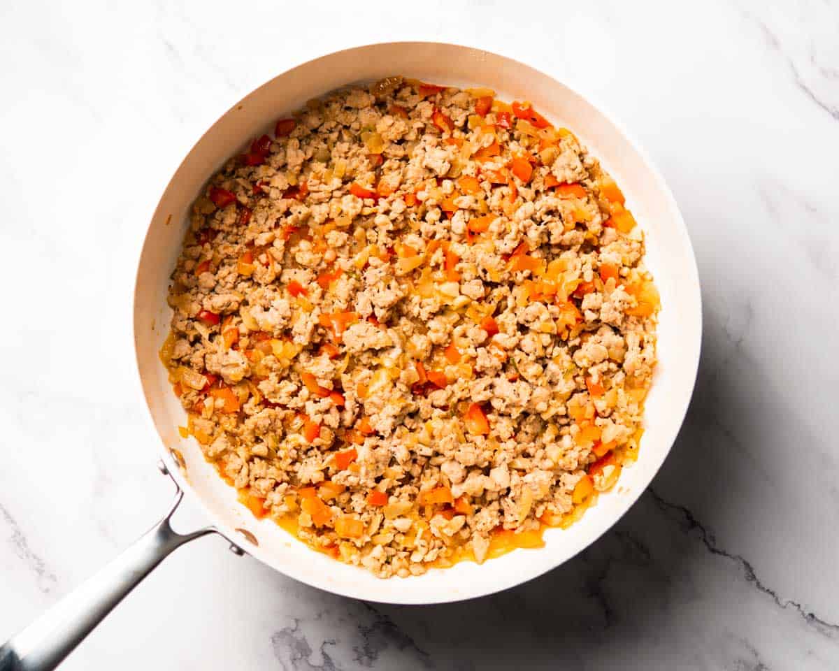 onion, bell pepper and ground chicken sauteing in a skillet