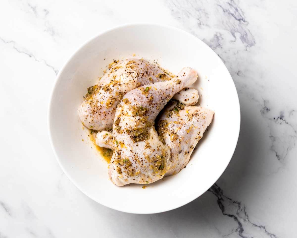 whole chicken legs and marinade mixed together in a bowl