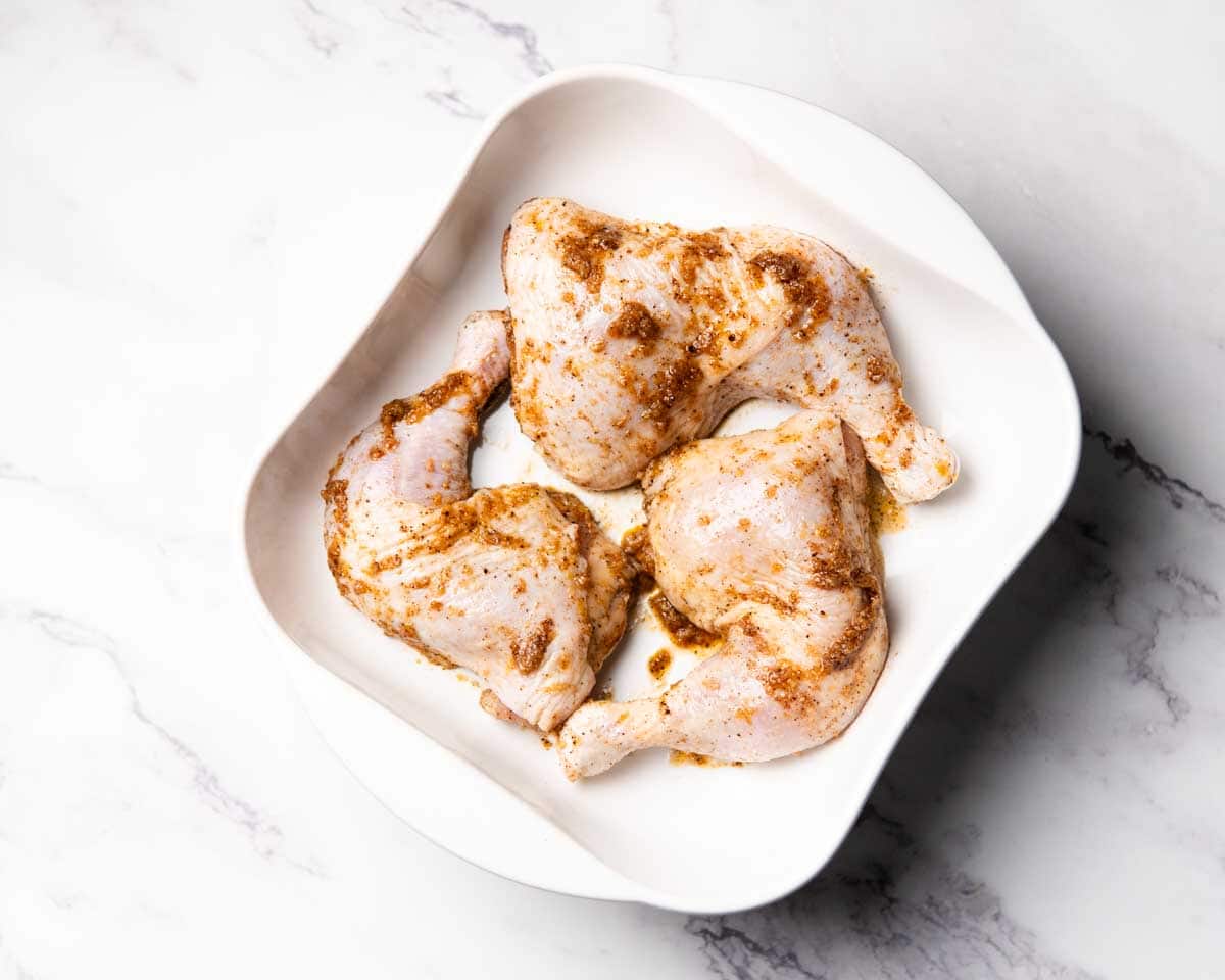 uncooked seasoned jerk chicken legs in baking dish