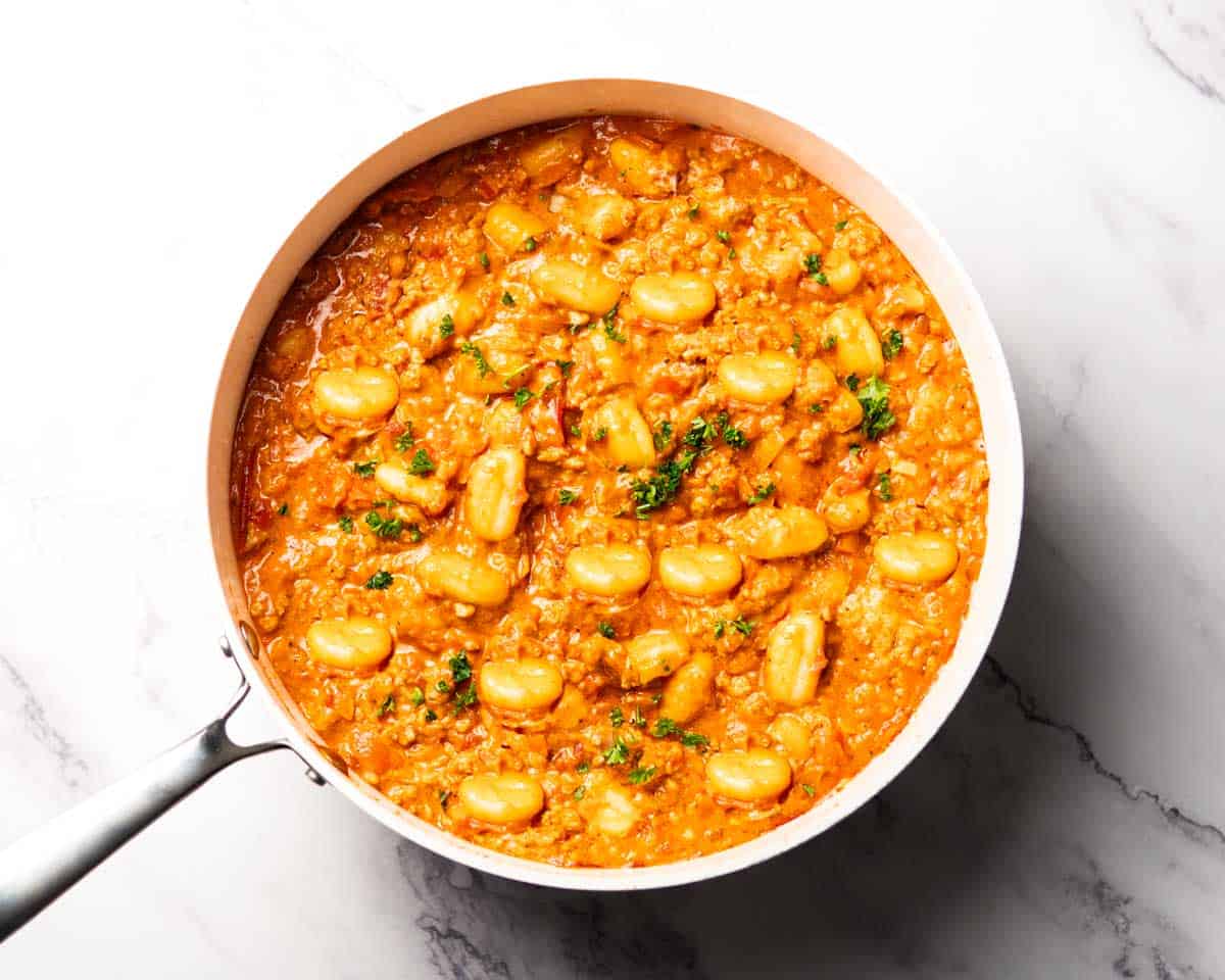 gnocchi cooking with ground chicken sauce in a skillet