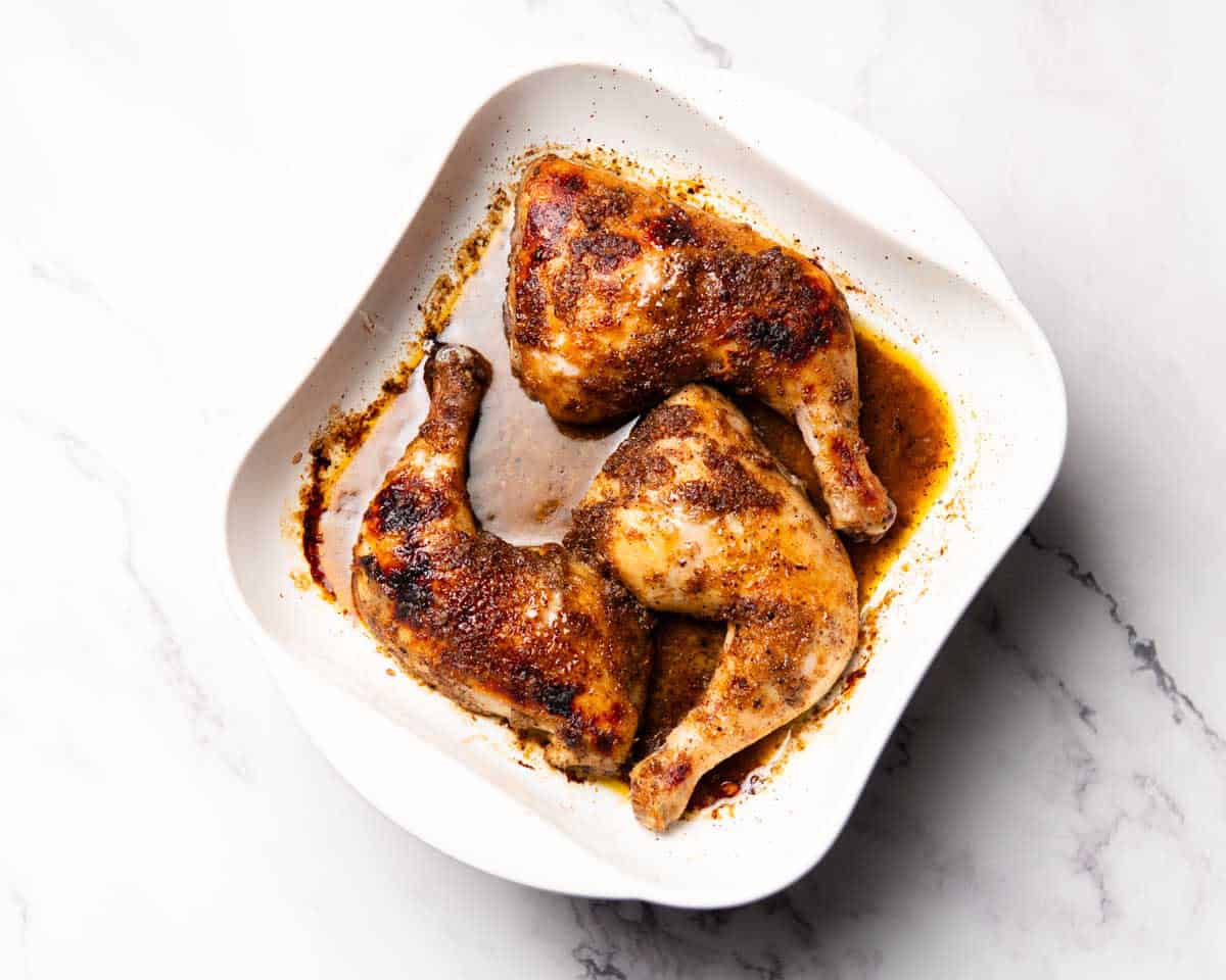 baking dish containing cooked jerk chicken leg quarters