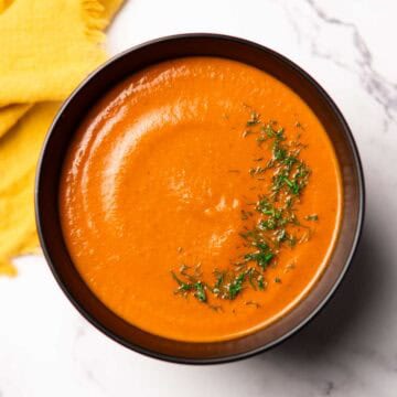 tomato dill soup in a bowl garnished with chopped dill