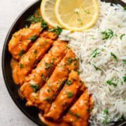 tomato chicken served on a black plate with rice