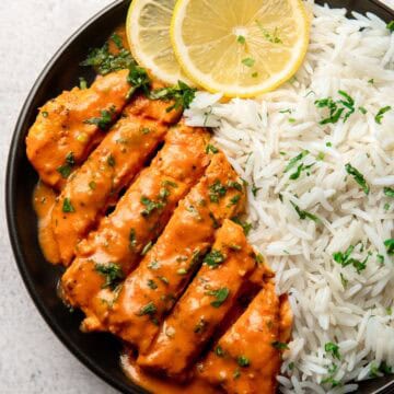 tomato chicken served on a black plate with rice